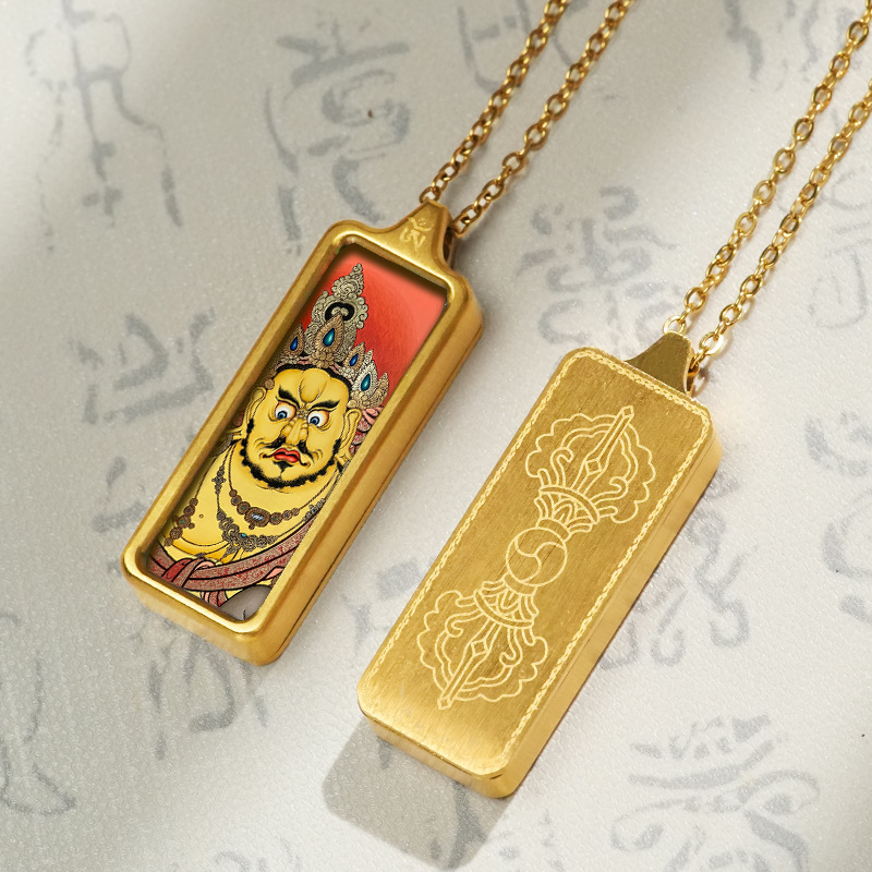 Gold pendant with a face design on a chain against a textured background