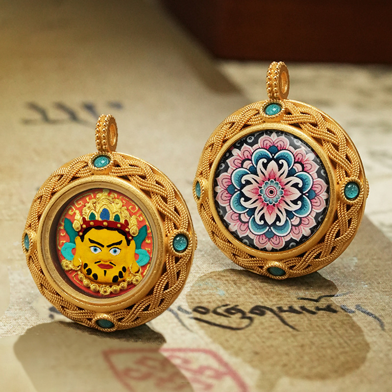 Two ornate gold pendants with colorful designs on a textured surface.