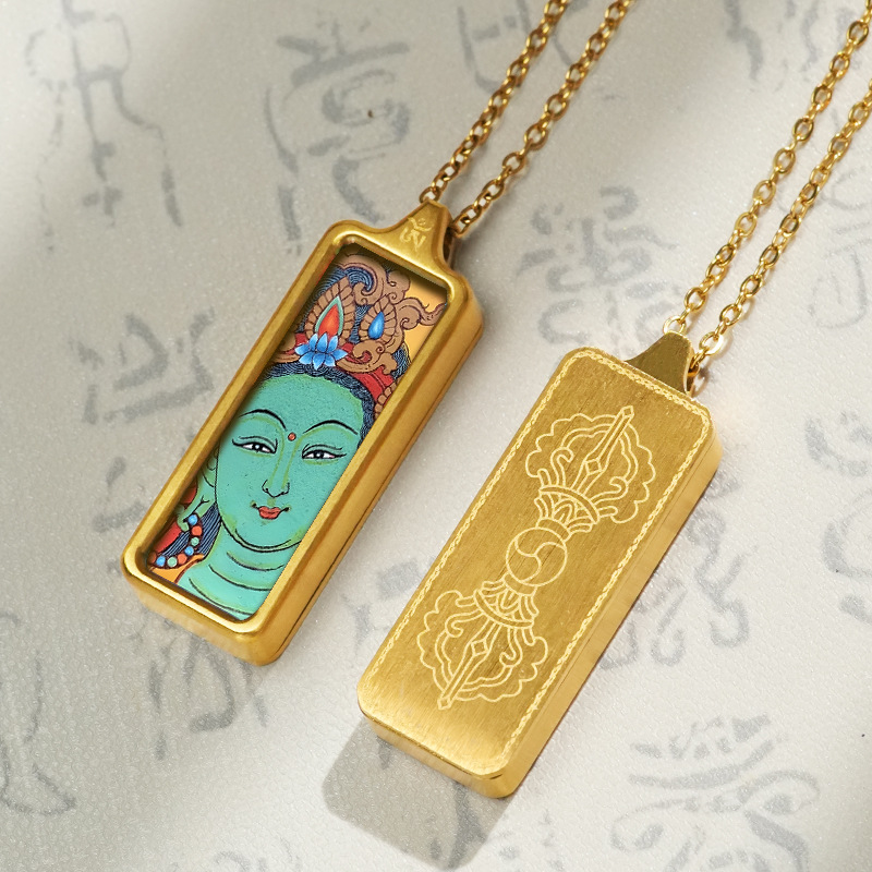 Gold pendant with a face design on a textured gray background