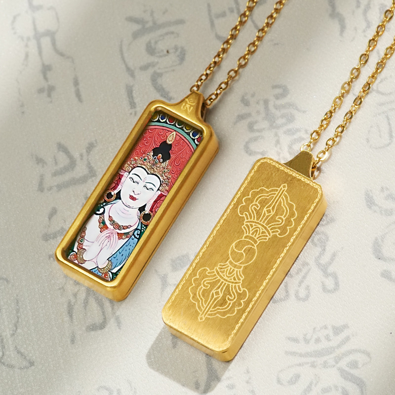 Gold pendant with a face on one side and engraved design on the other, on a textured gray background.
