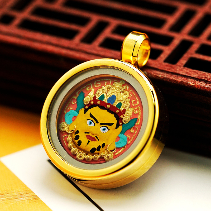 Gold pendant with a colorful face design on a wooden surface